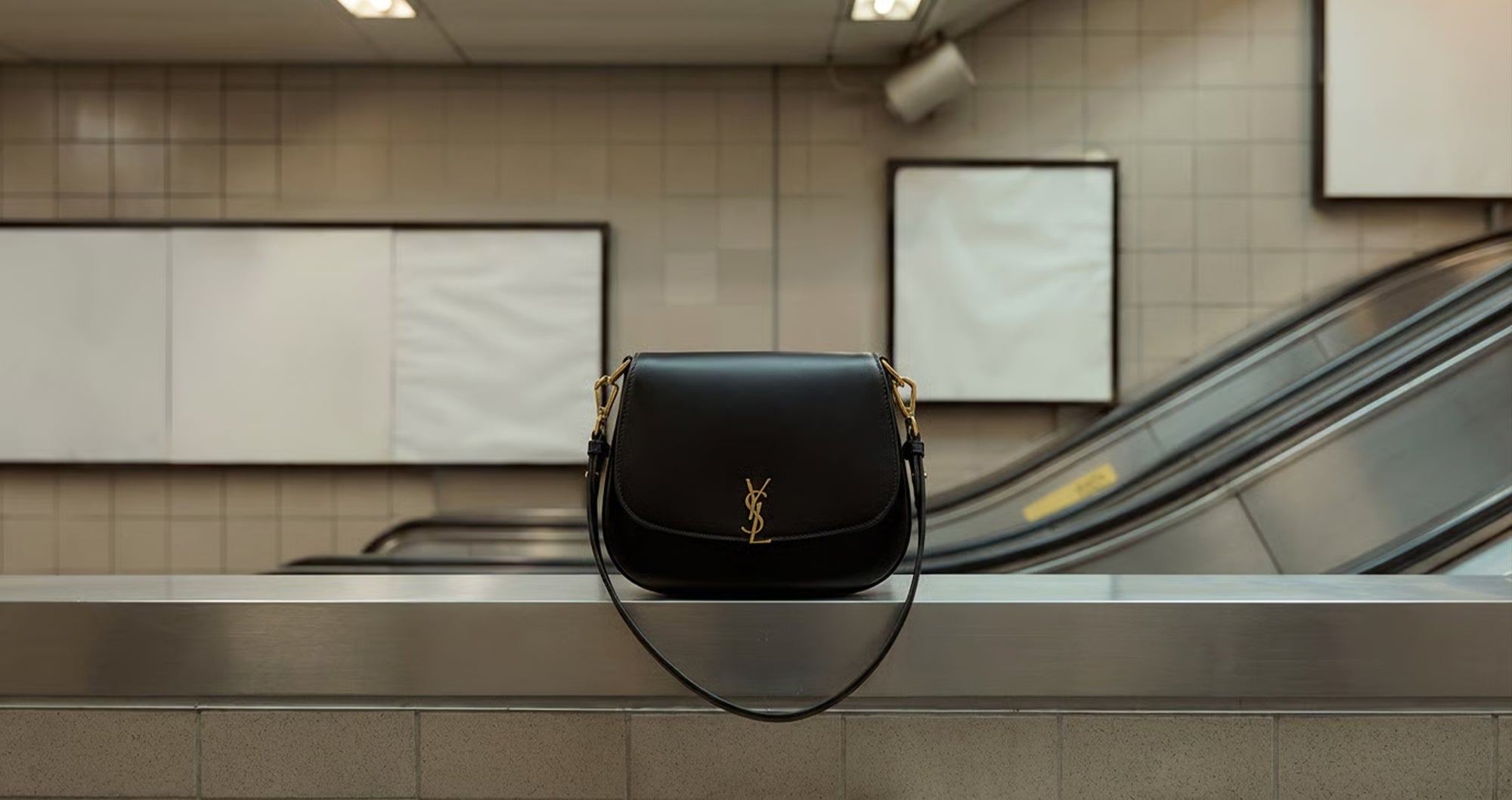 Black Saint Laurent shoulder bag resting on an escalator handrail