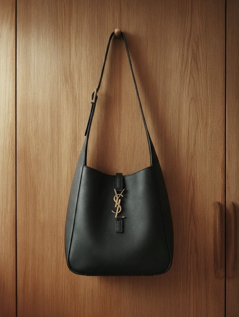 Black leather hobo bag hanging on a wooden door