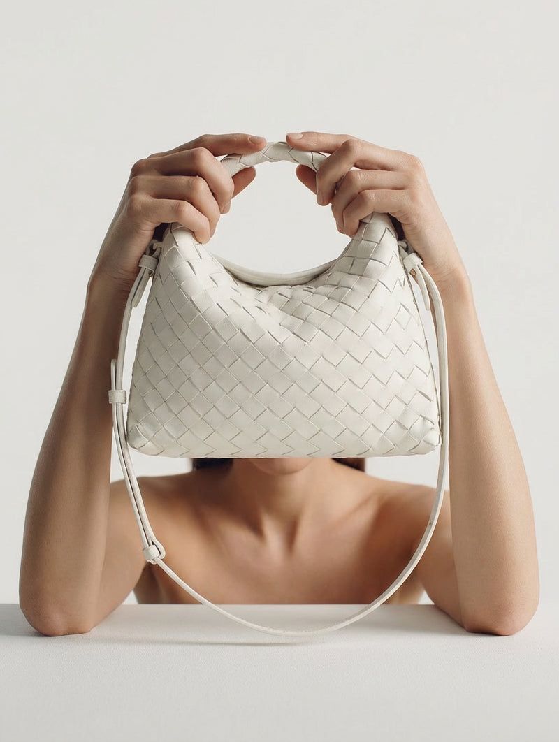 Woman holding a white woven leather bag in front of her face